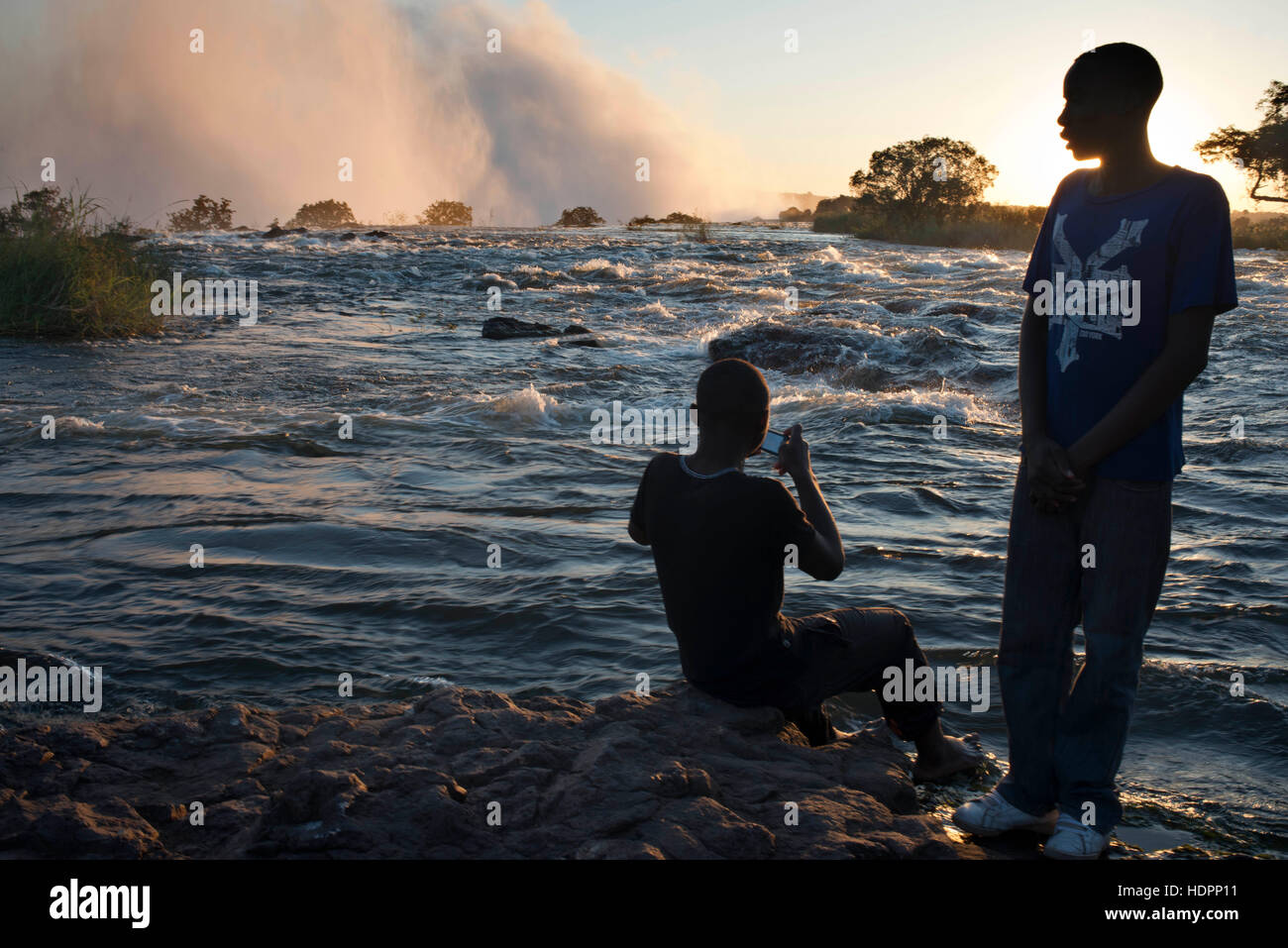 I turisti locali visitare il Victoria Falls. Queste sono tra le più spettacolari cascate nel mondo. Il fiume Zambesi, che si trova a più di 2 km di larghezza Foto Stock