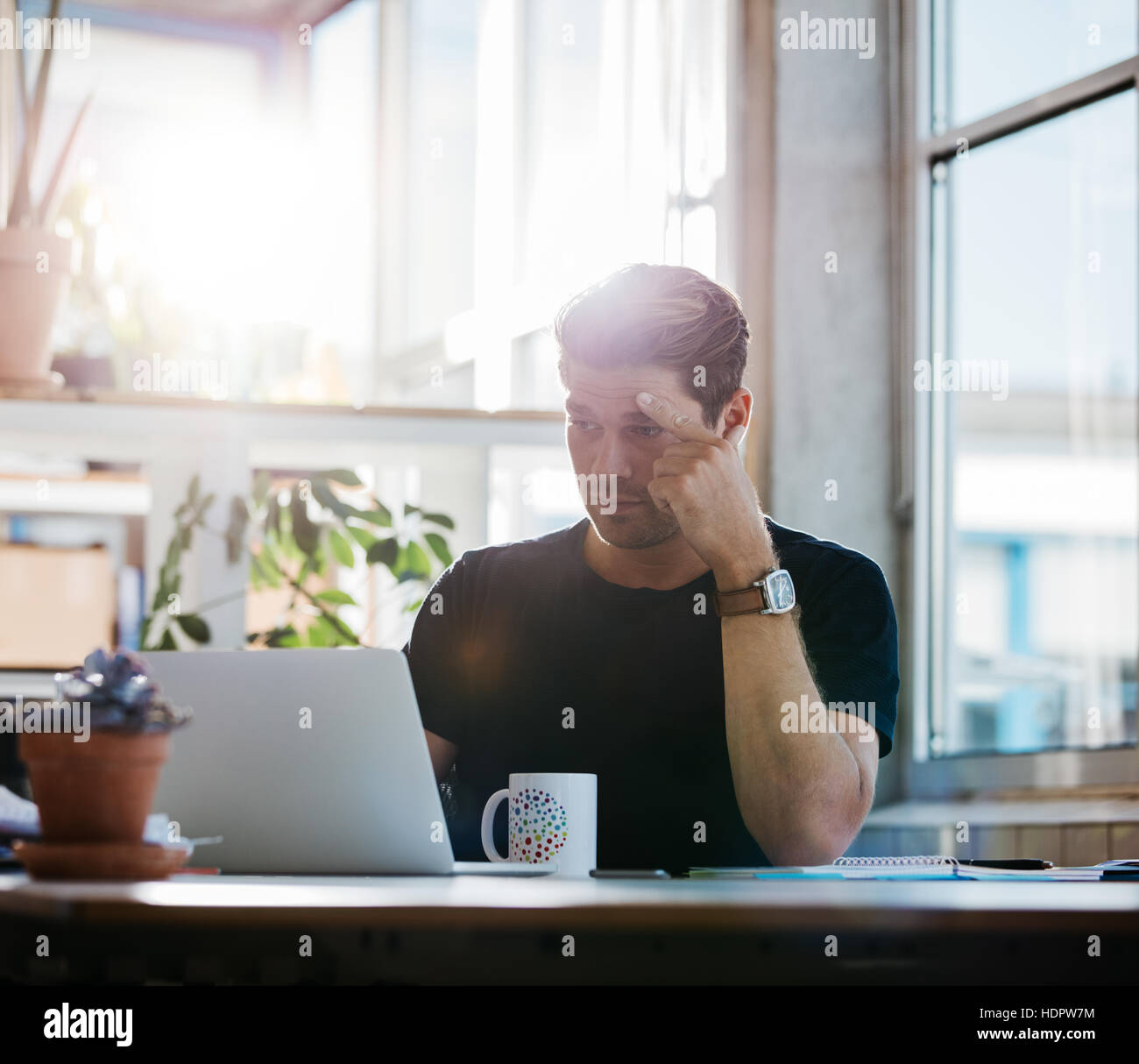 Giovane uomo d affari con stress guardando al suo computer portatile in ufficio. Executive maschio concentrare sul lavoro. Foto Stock