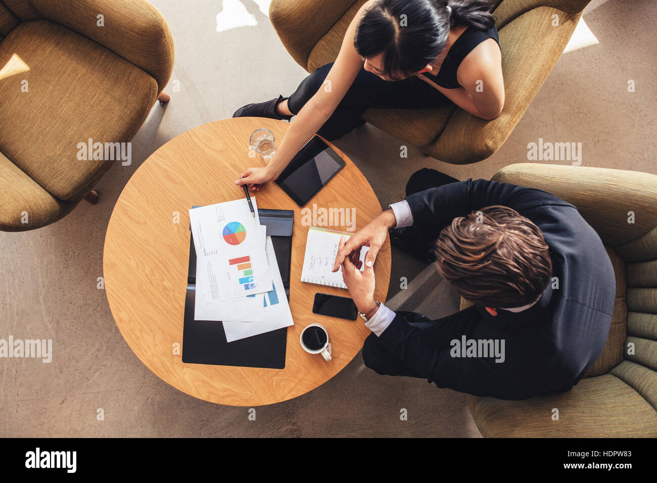 Vista superiore del collega di lavoro seduta a tavola con grafici durante la riunione aziendale. Imprenditore e imprenditrice a discutere di un nuovo progetto mentre sitti Foto Stock