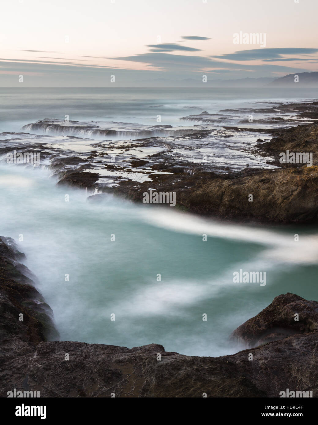 Mare mosso catturate con una lenta velocità di otturatore a creare una rilassante scena con acqua che scorre sulla roccia lavica con un buon effetto di movimento Foto Stock