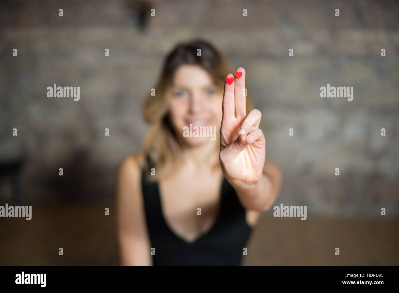 Due cuori rossi sulla donna con mano sorridente ragazza bionda in background, simbolo di amore e di rapporto Foto Stock