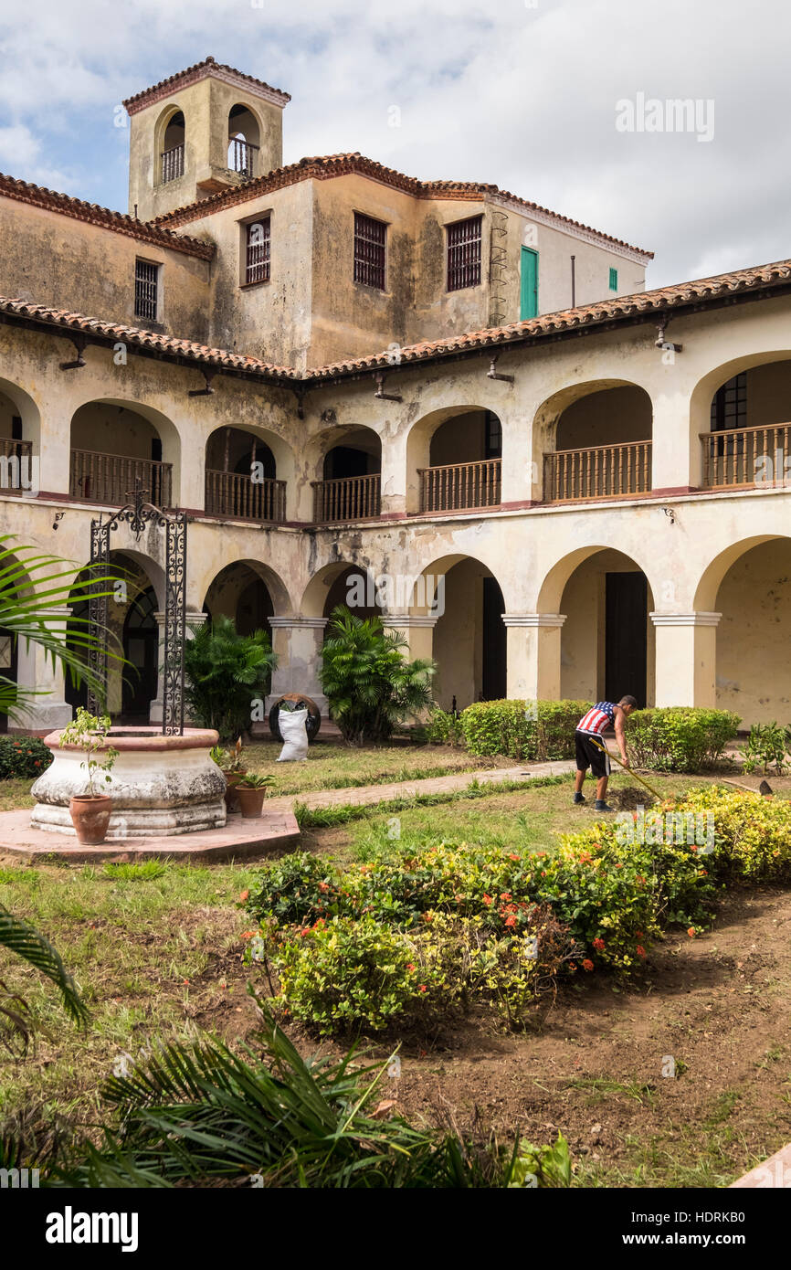 La gioventù in bandiera americana di T-shirt lavorando sul giardino di San Juan de Dios museum, Camaguey, Cuba Foto Stock