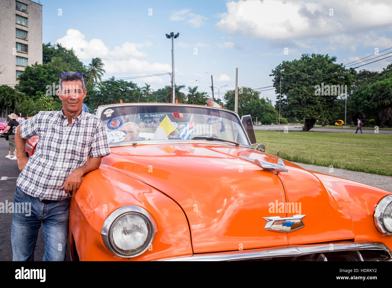 Chauffeur in posa con il suo vecchio americano degli anni cinquanta, cabriolet auto in Piazza della Rivoluzione, La Havana, Cuba. Foto Stock