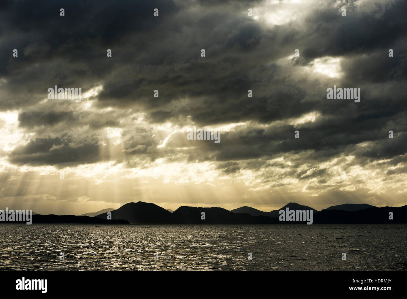 Raggi del sole attraverso le nuvole scure al tramonto sul canale di Douglas; British Columbia, Canada Foto Stock