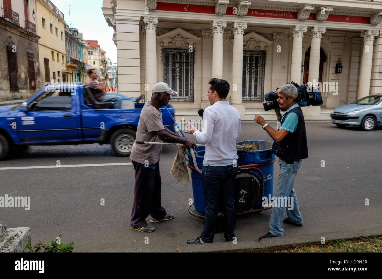 Tv cubana equipaggio intervistando il pulitore di via il giorno dopo Fidel Castri e fortezze della morte è stato annunciato come un uomo passa dietro seduti su una sedia nel retro del Foto Stock Tv cubana equipaggio intervistando il pulitore di via il giorno dopo Fidel Castri e fortezze della morte è stato annunciato come un uomo passa dietro seduti su una sedia nel retro del Foto Stock