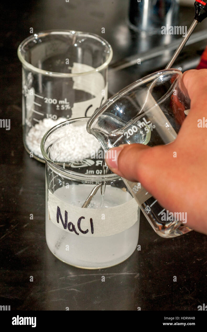 Un bicchiere di acqua viene versata in cloruro di sodio essiccato polvere  durante un esperimento in una San Clemente, CA, soluzione laboratorio di  chimica Foto stock - Alamy