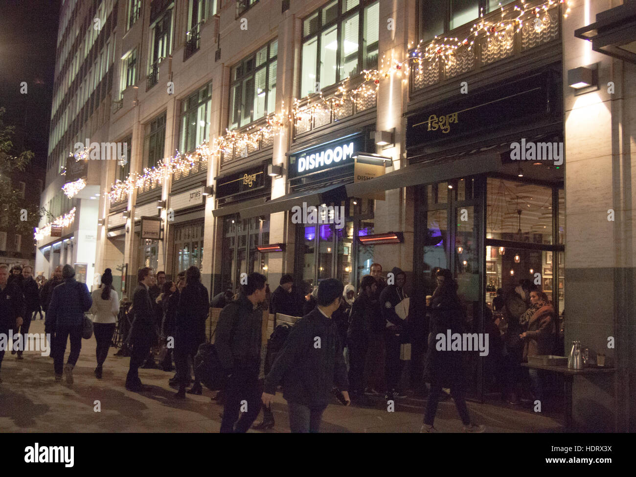 La gente in coda di notte fuori del ristorante in London West end di notte - Dishoom, St Martins Lane WC2 Foto Stock