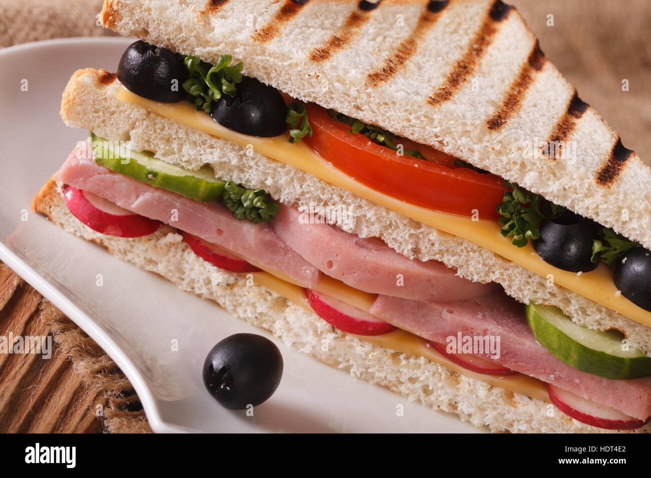 Sandwich con prosciutto e formaggio e verdure macro su una piastra sul tavolo orizzontale. Foto Stock