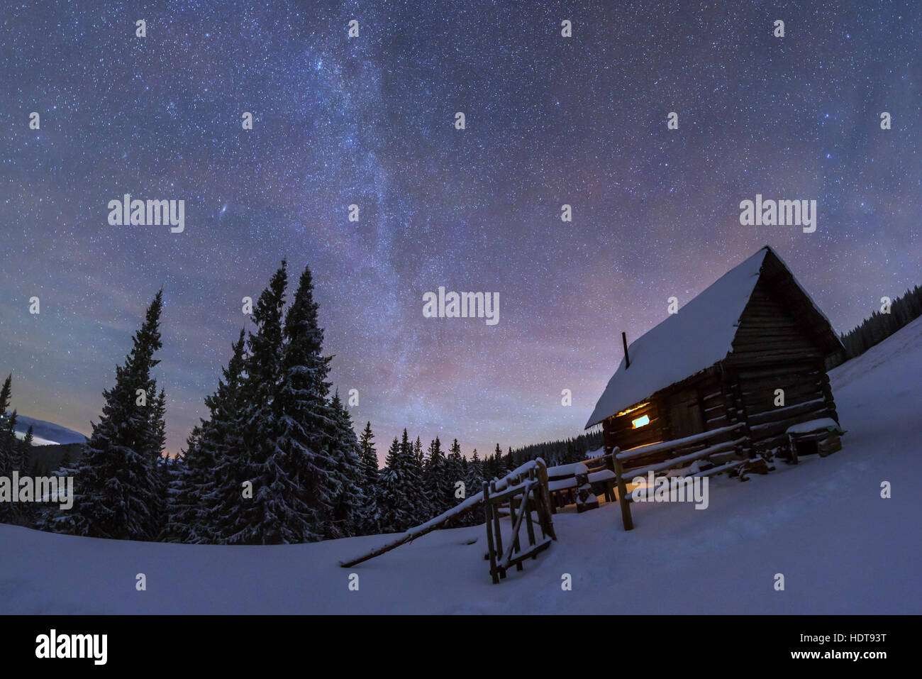 Fantastico paesaggio notturno incandescente dalla via lattea. Drammatica scena invernale con casa nevoso. Carpazi, Ucraina, l'Europa. Foto Stock