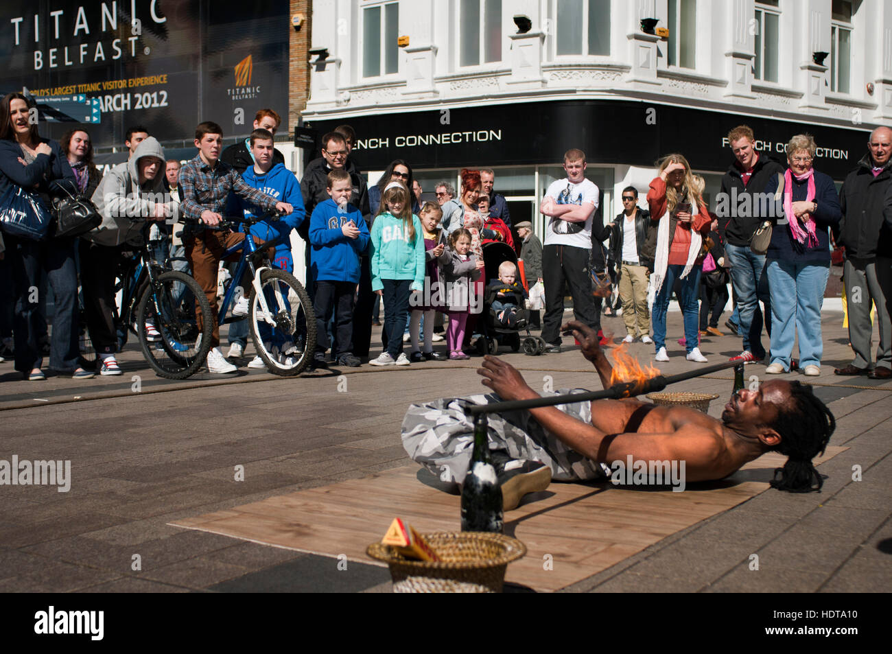 Un giocoliere tenta di passare sotto il fuoco in piazza Arthur, Belfast, Irlanda del Nord, Regno Unito. Arthur Square è anche noto come Cornmarket (precedentemente era k Foto Stock