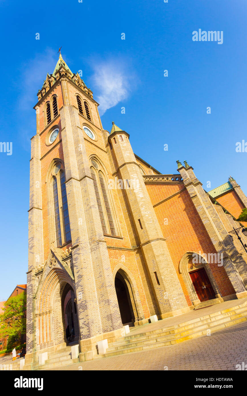 Inclinato di entrata anteriore e il cortile del mattone steeple a a Myeongdong Cathedral su un cielo azzurro giorno a Seul, Corea del Sud Foto Stock