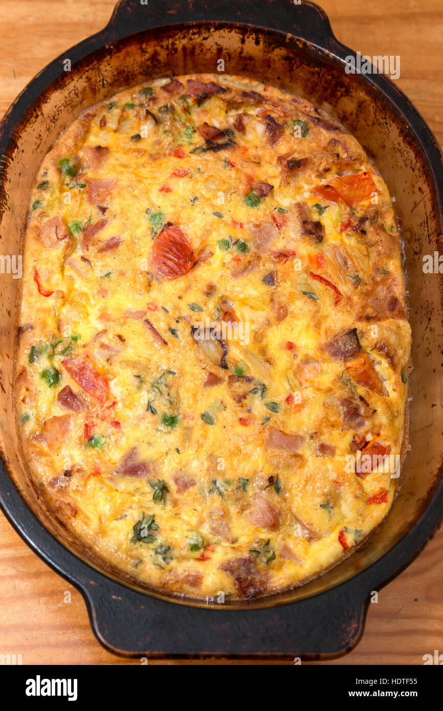 Stile Italiano frittata, uova ricetta pomodori cipolle, i piselli e i peperoni in capsula di vetro Foto Stock