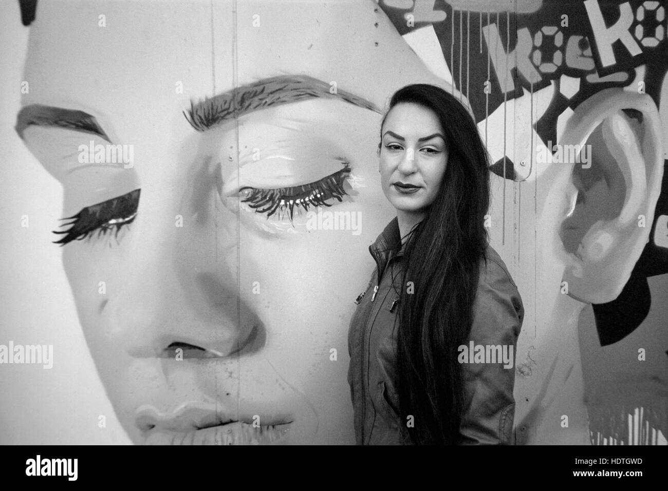 Giovane bella femmina pone accanto alla parete art graffiti southsea England Regno Unito Foto Stock