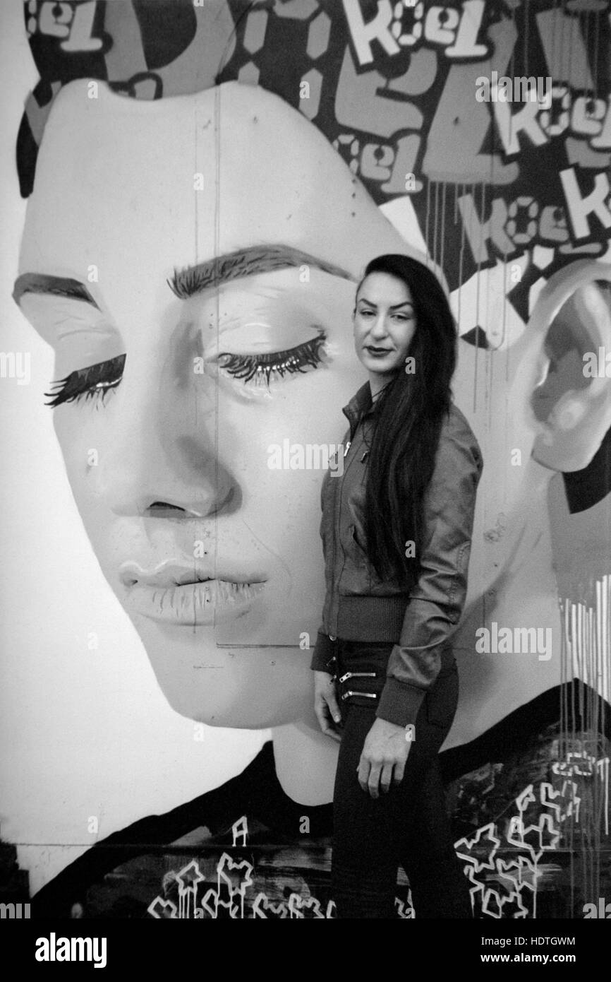 Giovane bella femmina pone accanto alla parete art graffiti southsea England Regno Unito Foto Stock