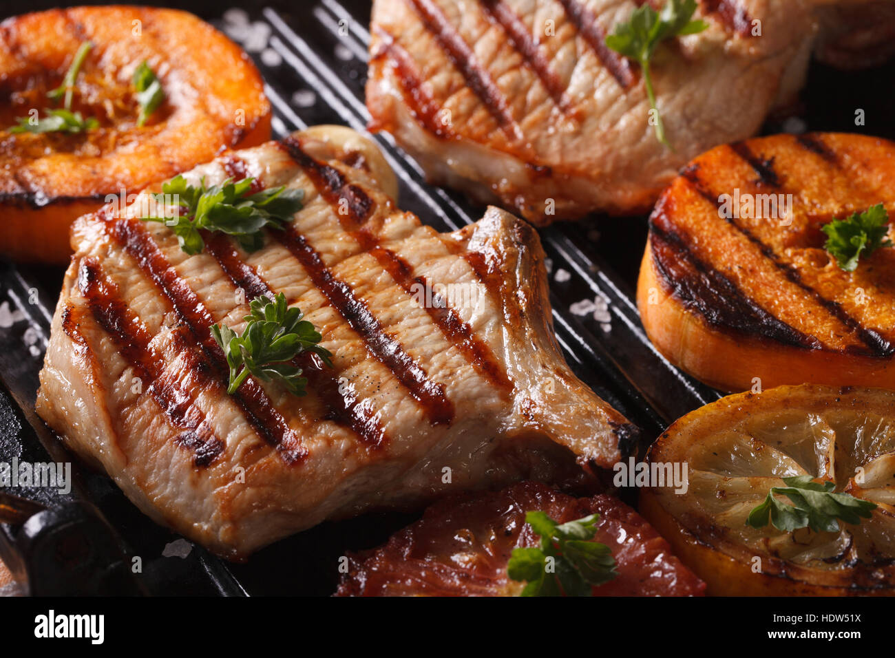 Carne di maiale alla griglia bistecca e zucca su un grill. Horizontal Macro, stile rustico Foto Stock