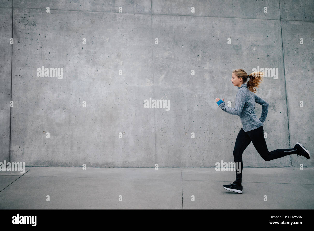 Immagine laterale di una giovane donna sana che corre all'aperto. fitness modella che fa jogging al mattino. Foto Stock