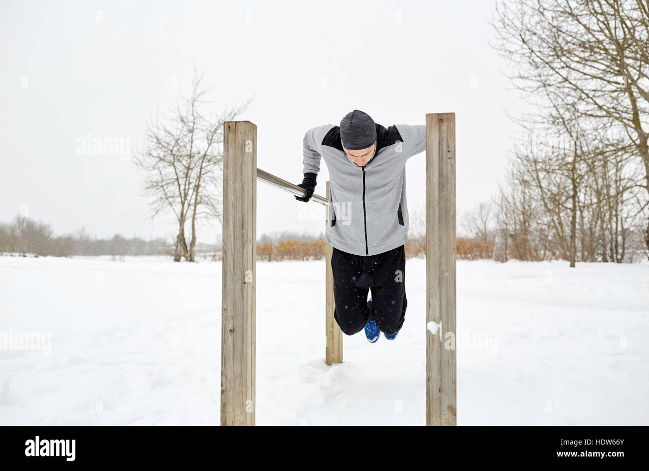 Giovane uomo esercitando sulle barre parallele in inverno Foto Stock