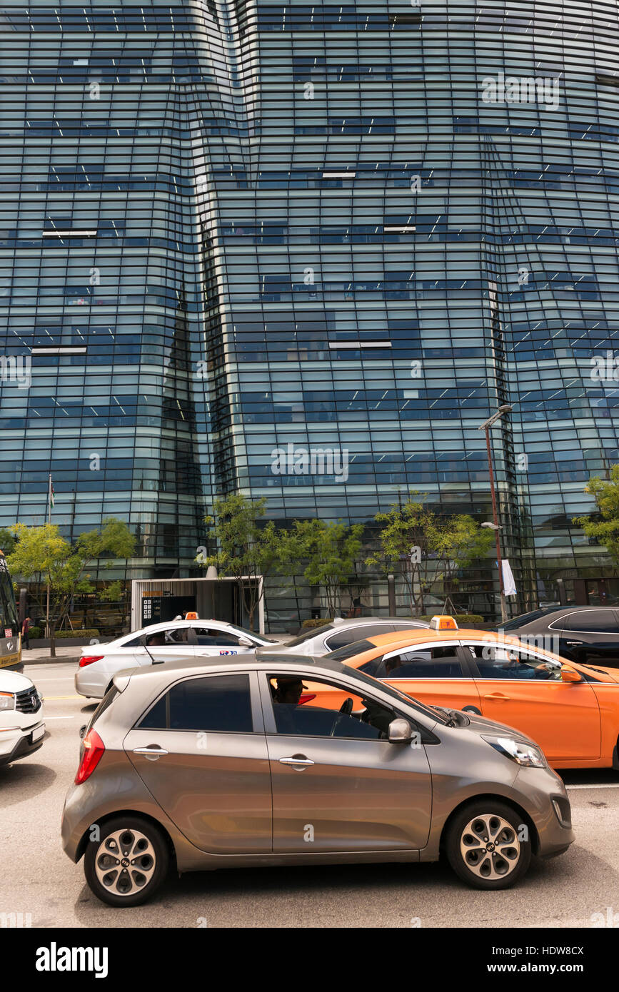 Pendolari sedersi nelle loro automobili nel traffico su strada con la facciata di vetro di un edificio per uffici in background, Seul in Corea del Sud Foto Stock