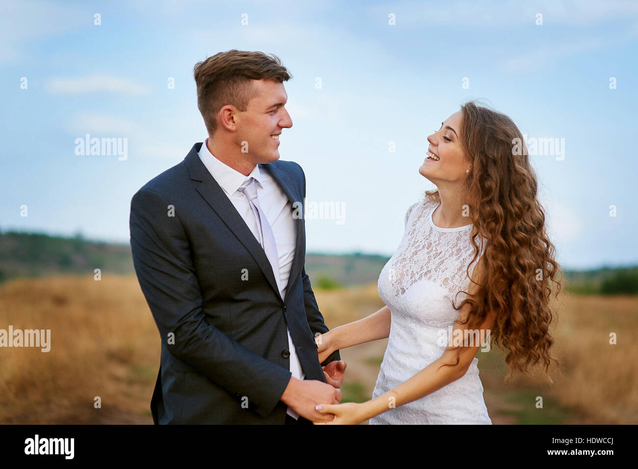 Felice sposa e lo sposo a camminare in un campo in giorno di nozze Foto Stock