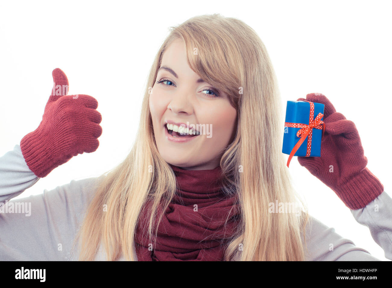 Foto d'epoca, donna sorridente in guanti holding avvolto regalo per Natale o altra celebrazione e mostrando pollice su sfondo bianco Foto Stock