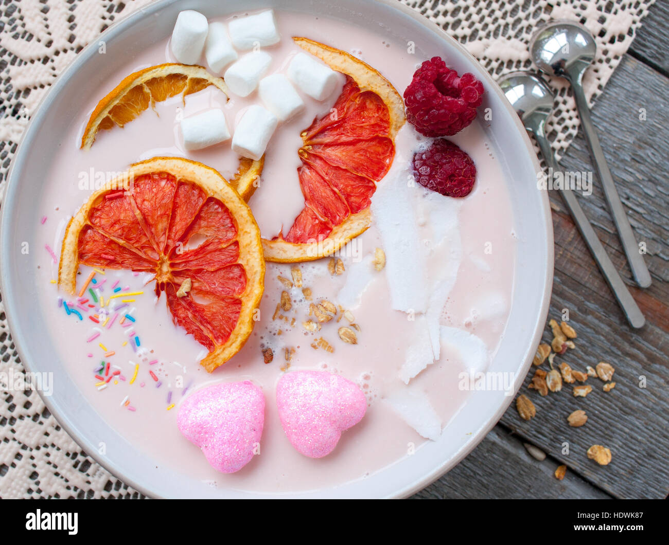 Frullati rosa con lampone, noce di cocco, arance e granola. La prima colazione il giorno di San Valentino. Foto Stock