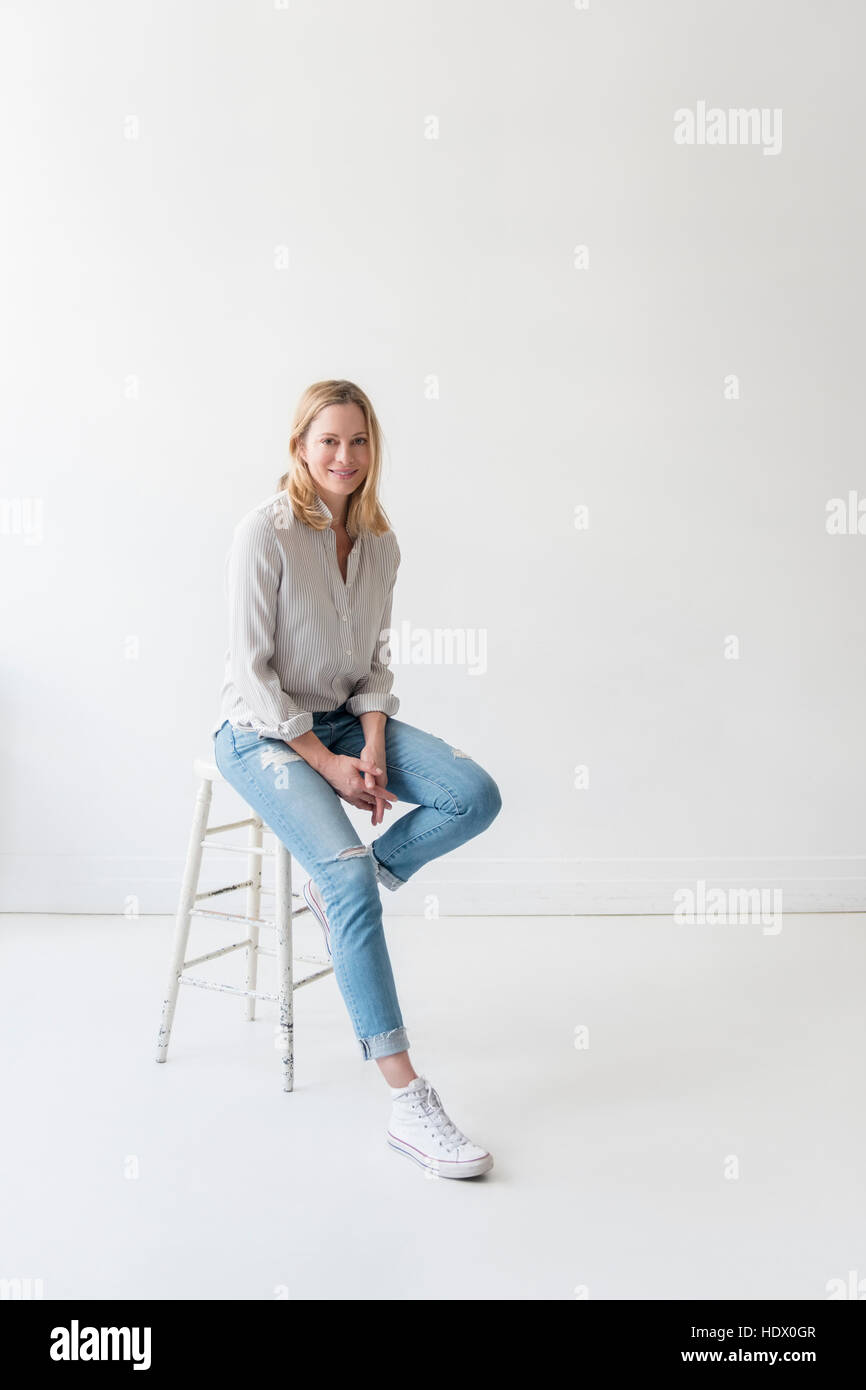 Caucasian donna seduta su uno sgabello Foto Stock