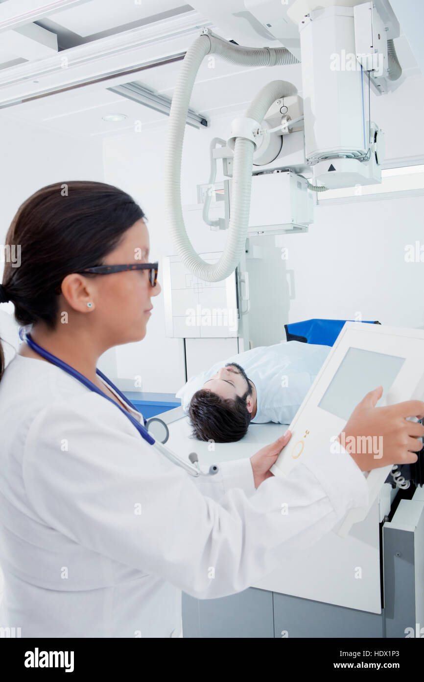 Medico di origine ispanica al pannello di comando della macchina a raggi x Foto Stock