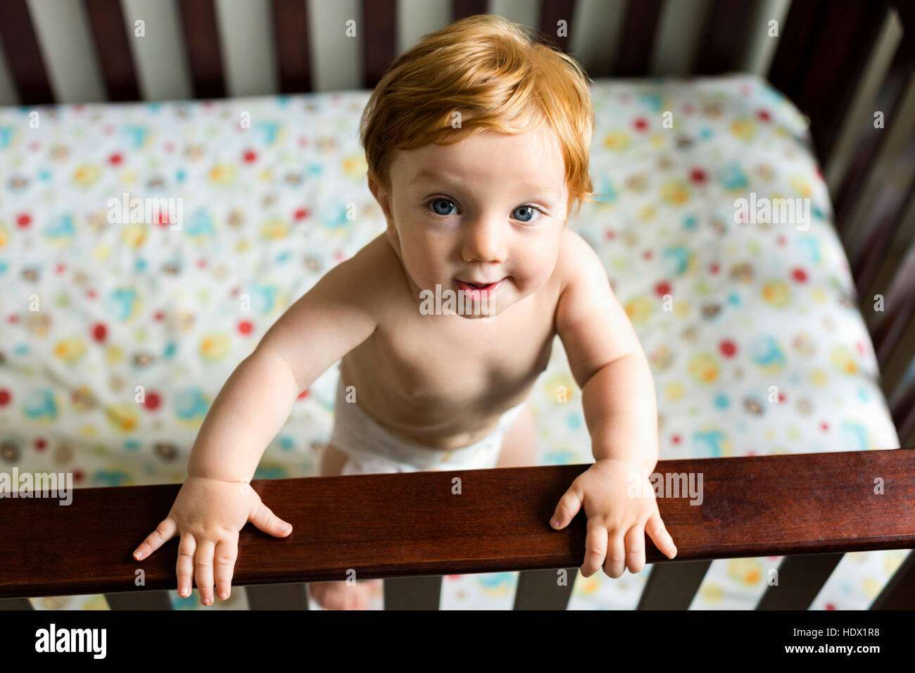 Ritratto di curioso Caucasian baby boy in piedi nel presepe Foto Stock