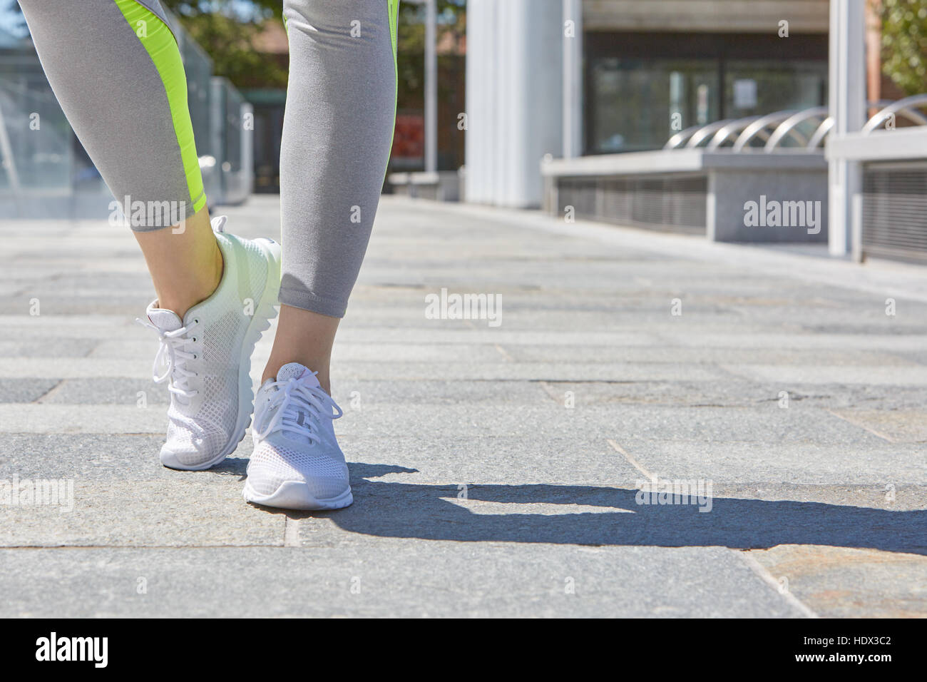Donna con bianco scarpe sportive pronto per essere eseguito all'aperto in città in una giornata di sole Foto Stock