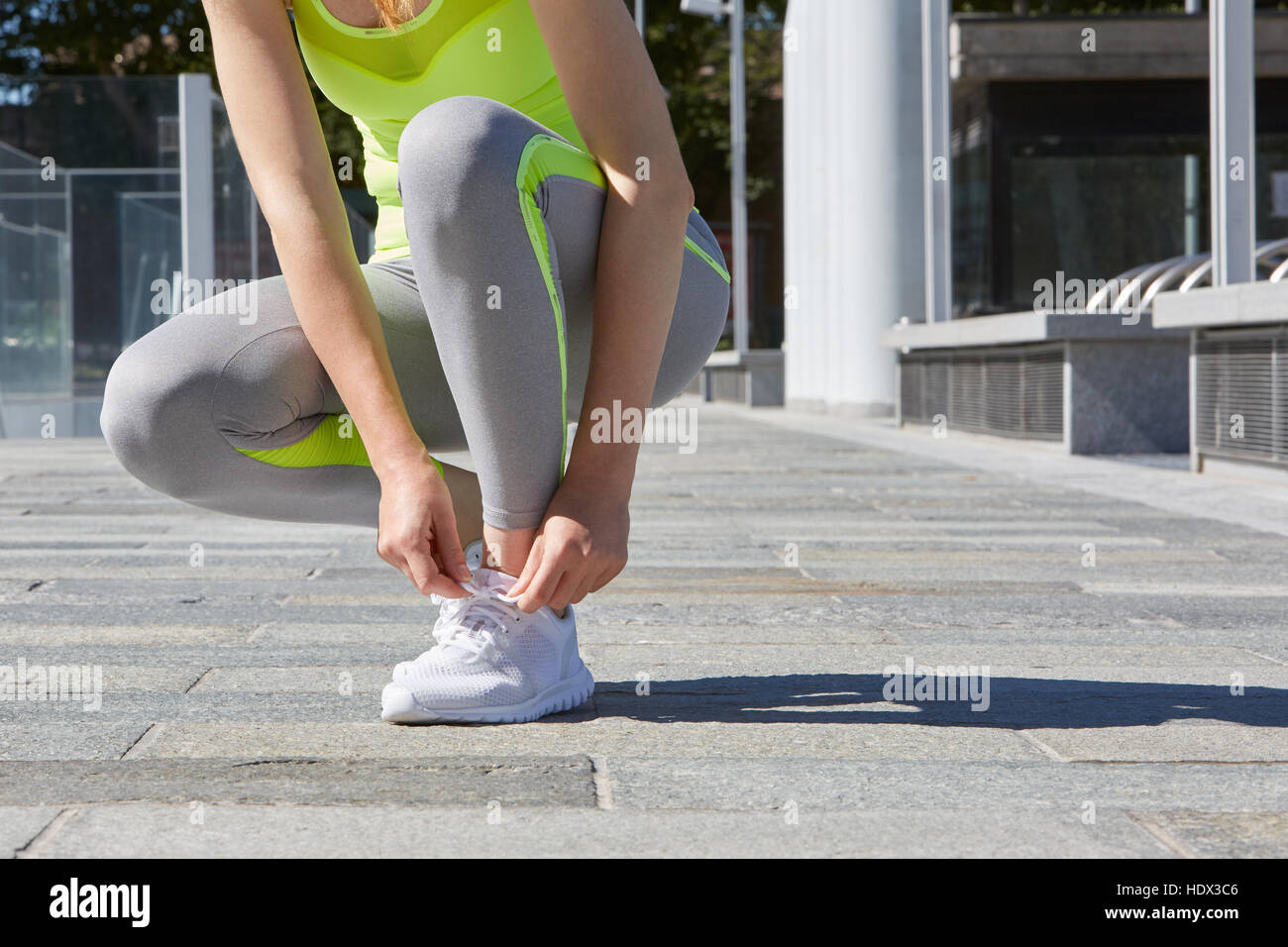 Legatura donna lacci delle scarpe prima di eseguire all'aperto nella città, alla luce del sole Foto Stock