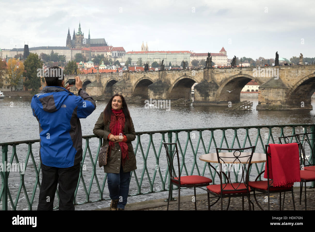 Un paio di scattare foto accanto al fiume Vltava a Praga con il ponte Carlo e il Castello di Praga in background Foto Stock
