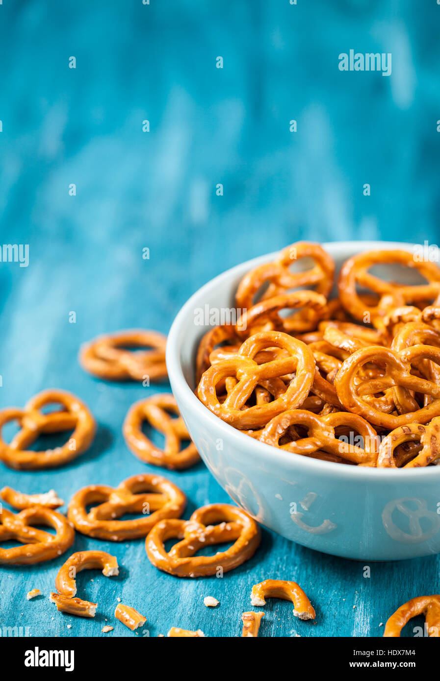 Snack salati mini pretzel nella ciotola blu sul tavolo di legno Foto Stock