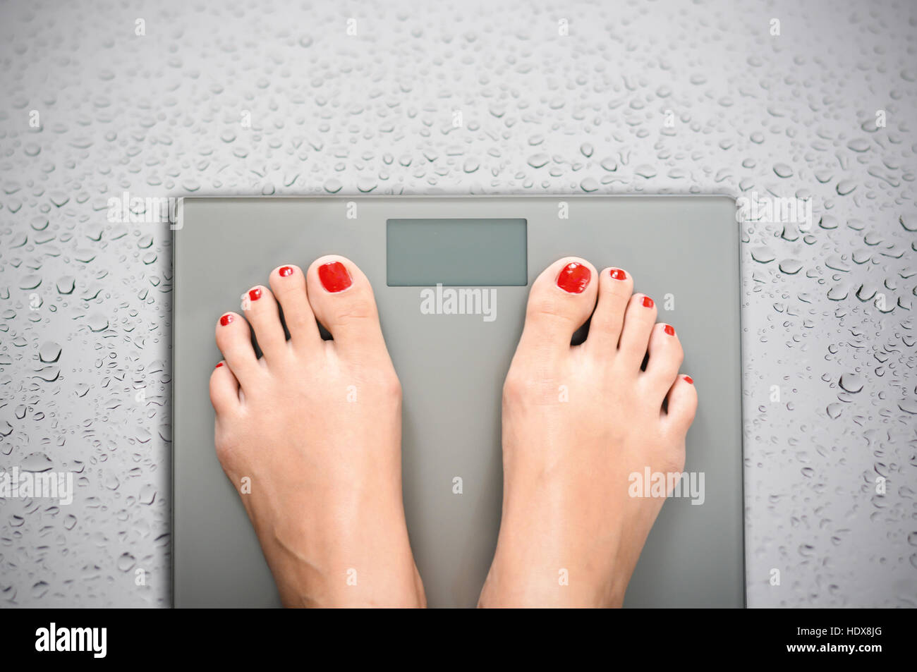 Aiutare a perdere chilogrammi con la donna piedi intensificazione su una scala di peso Foto Stock