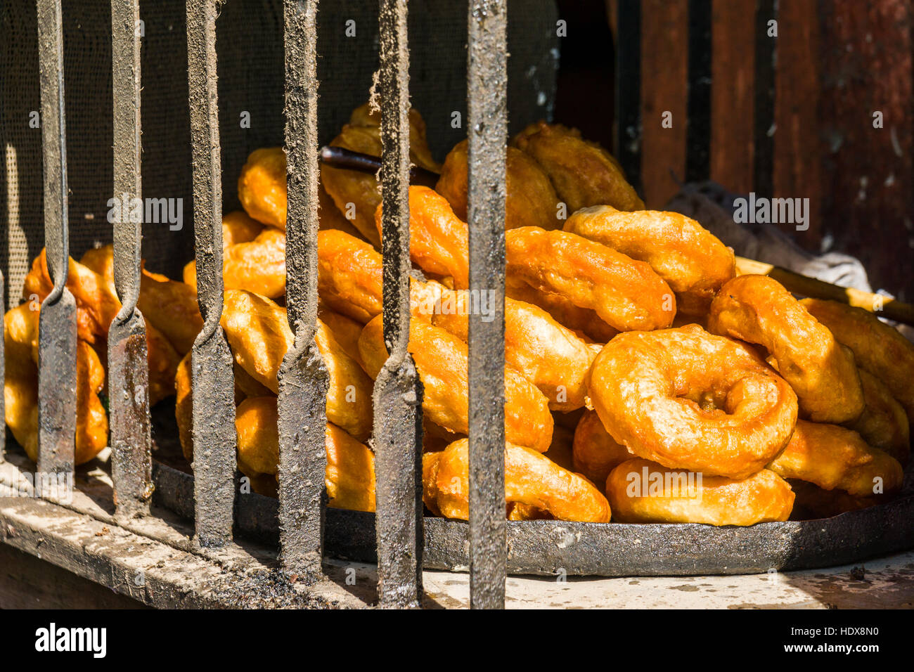 Un mazzetto di ciambelle fresche, tipica colazione nepalese, fritti in una grande padella Foto Stock