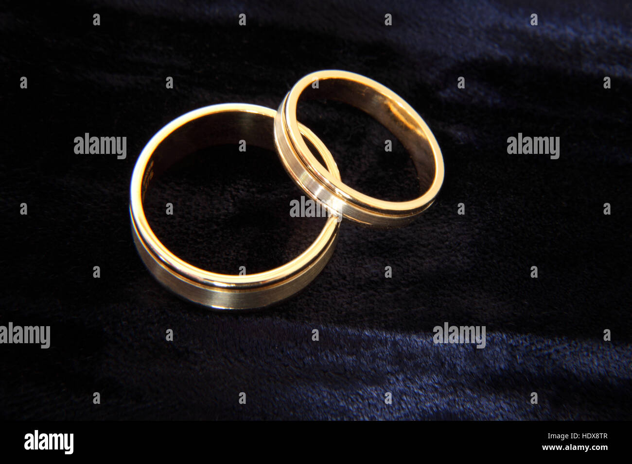 Una coppia di corrispondenti anelli di nozze utilizzando sia il bianco e il giallo oro, su un tampone di velluto. Foto Stock