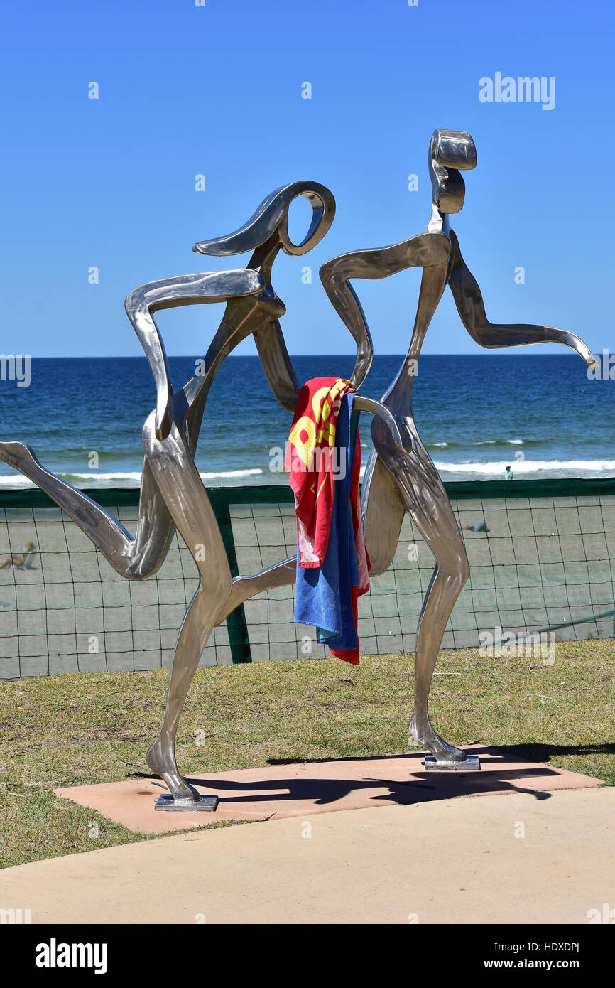 Lucido metallo in lega di scultura di maschi e femmine di jogging lungo la spiaggia dell'oceano in Gold Coast. Foto Stock