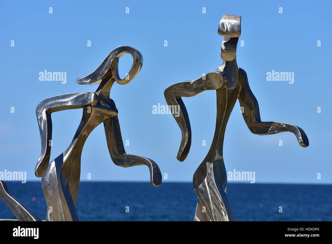 Lucido metallo in lega di scultura di maschi e femmine di jogging lungo la spiaggia dell'oceano in Gold Coast. Foto Stock