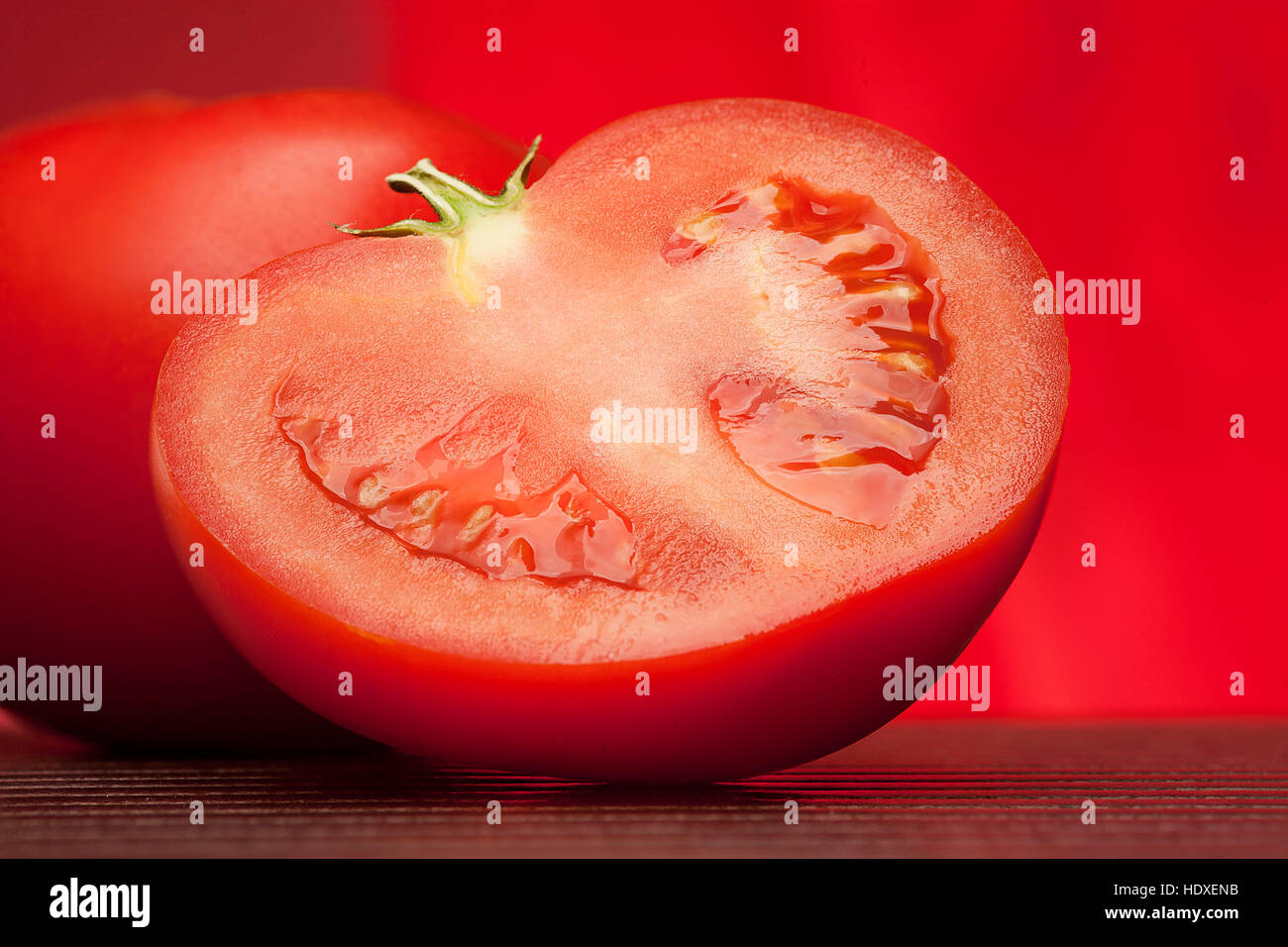 Semi di pomodoro fresco su tavolo e su sfondo rosso Foto Stock