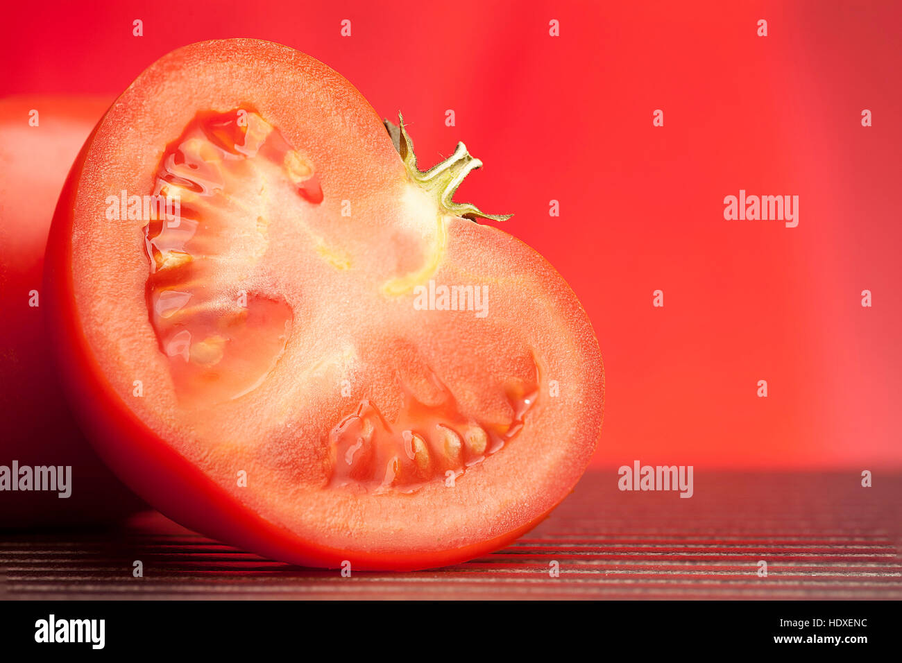 Mezzo fresco di pomodoro succosa su tavolo e su sfondo rosso Foto Stock