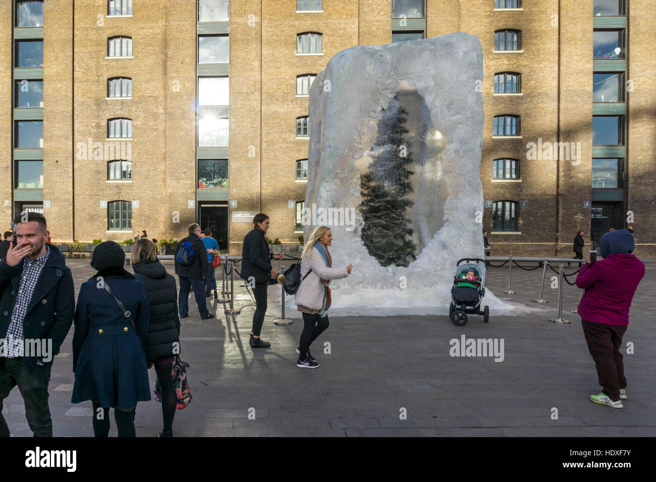La gente a prendere le fotografie di fronte a combattere il fuoco con il gelato, un albero di Natale racchiusi in un blocco di ghiaccio, di Alex Chinneck. Foto Stock