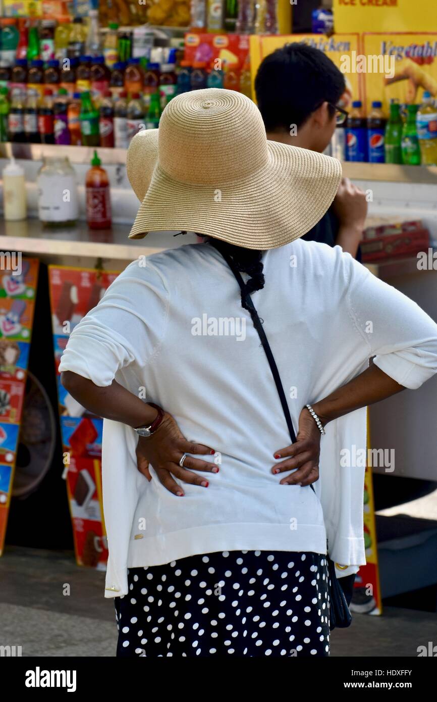 Una donna in piedi con le mani sui suoi fianchi mentre erano in attesa in linea per il cibo in un cibo carrello in Washington DC Foto Stock