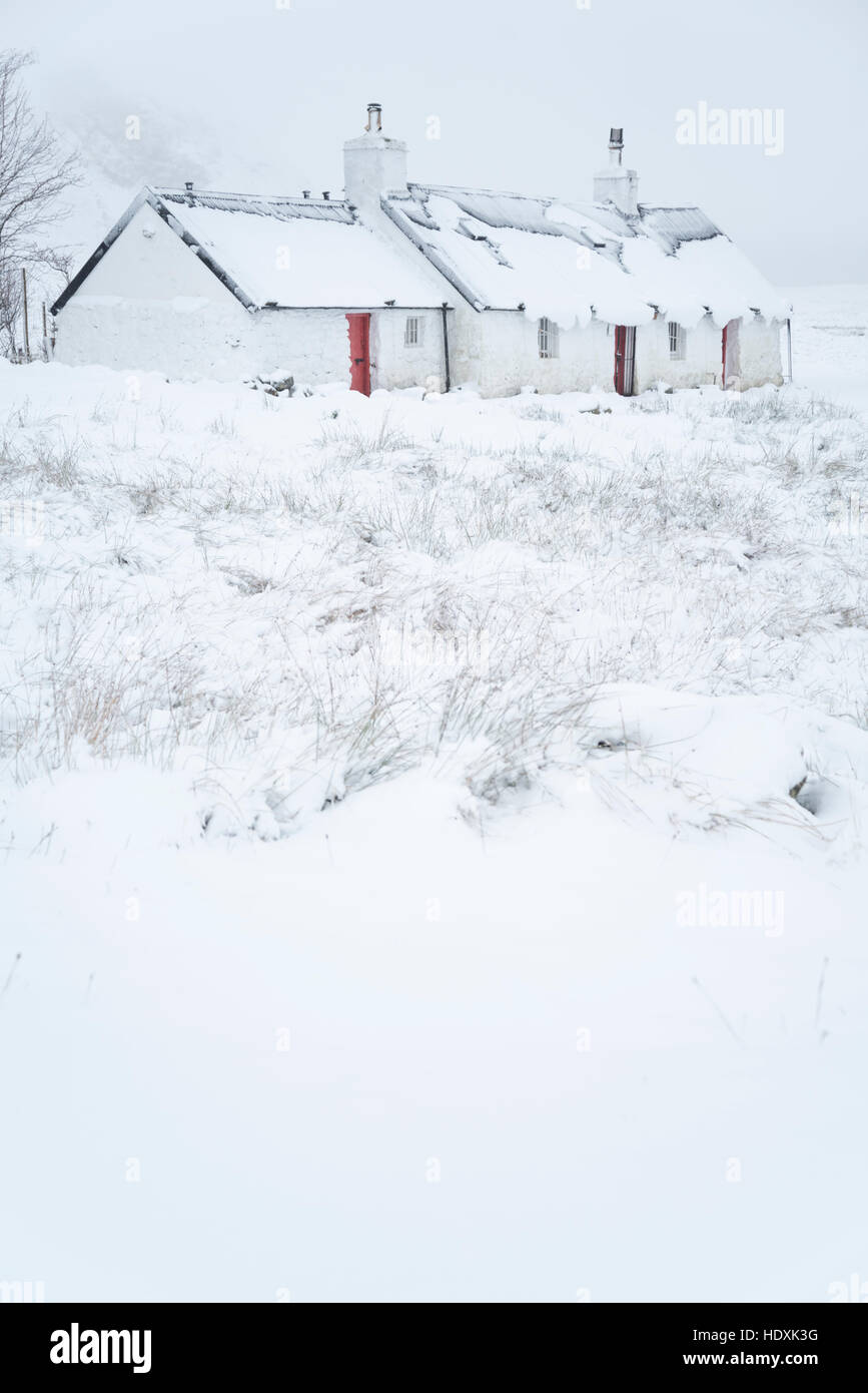 Coperte di neve cottage tradizionale coperta di neve in inverno nelle highlands scozzesi Foto Stock