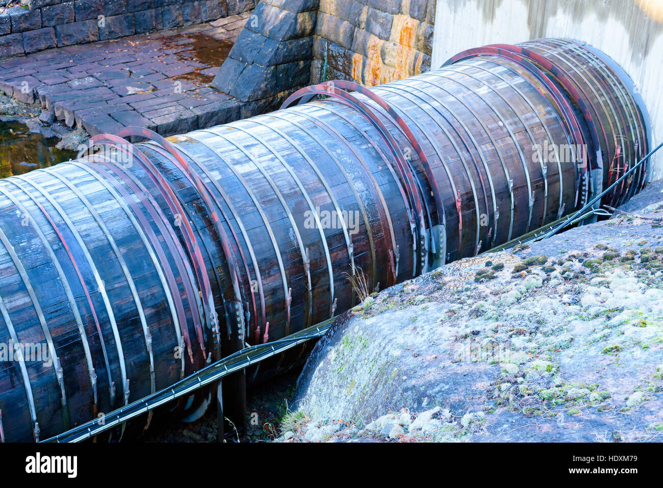 Di legno grande tubo di acqua a livello locale centrale idroelettrica. Tubo parzialmente coperto di ghiaccio sottile dopo una notte fredda. Foto Stock
