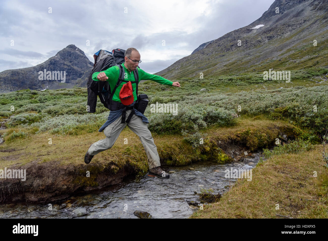 Escursionista salta creek, parco nazionale di Jotunheimen, Norvegia Foto Stock