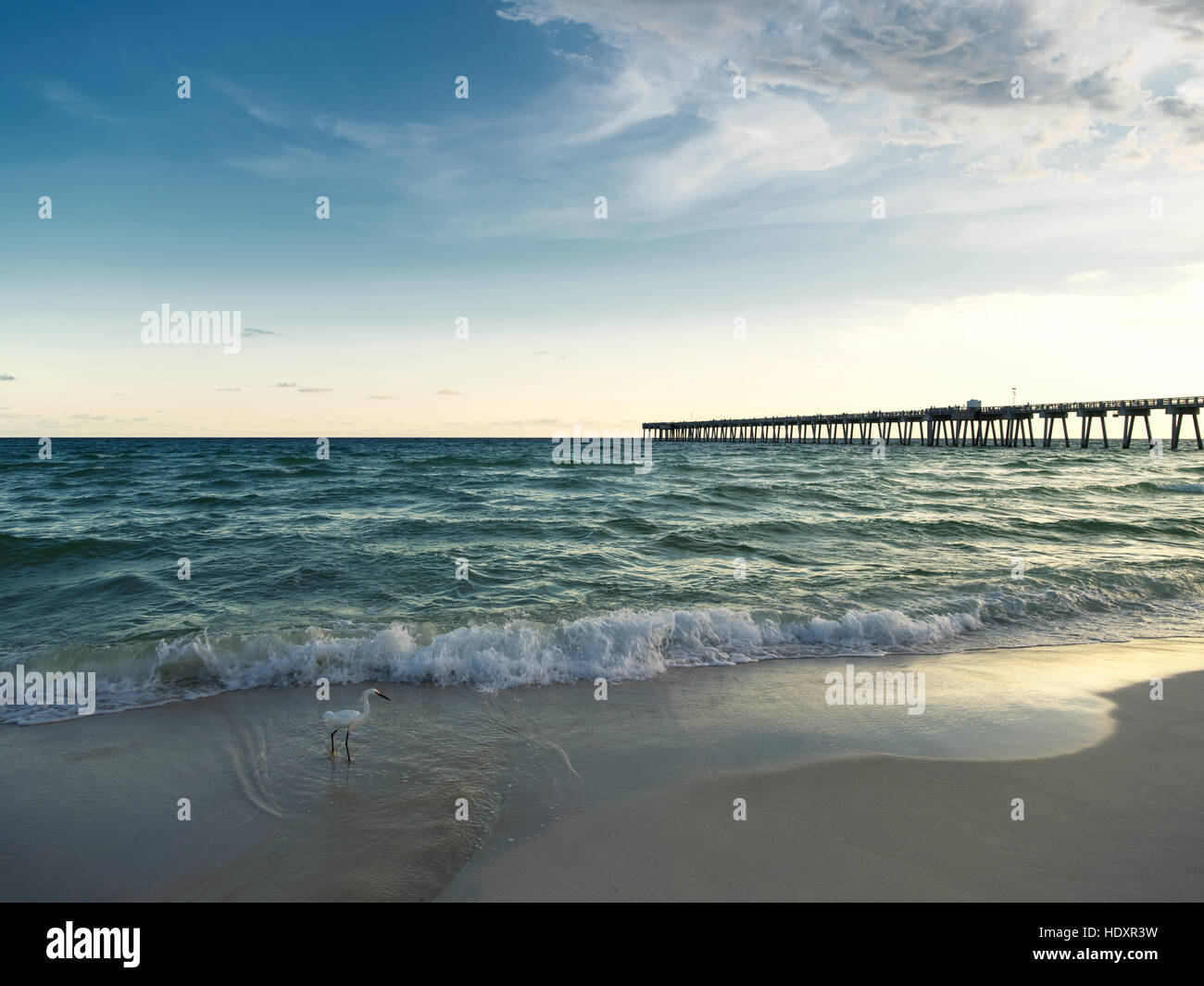 Un molo di pesca, un airone bianco e acque turchesi del Golfo costa al tramonto. Panama City Beach, Gulf Coast, Florida. Foto Stock