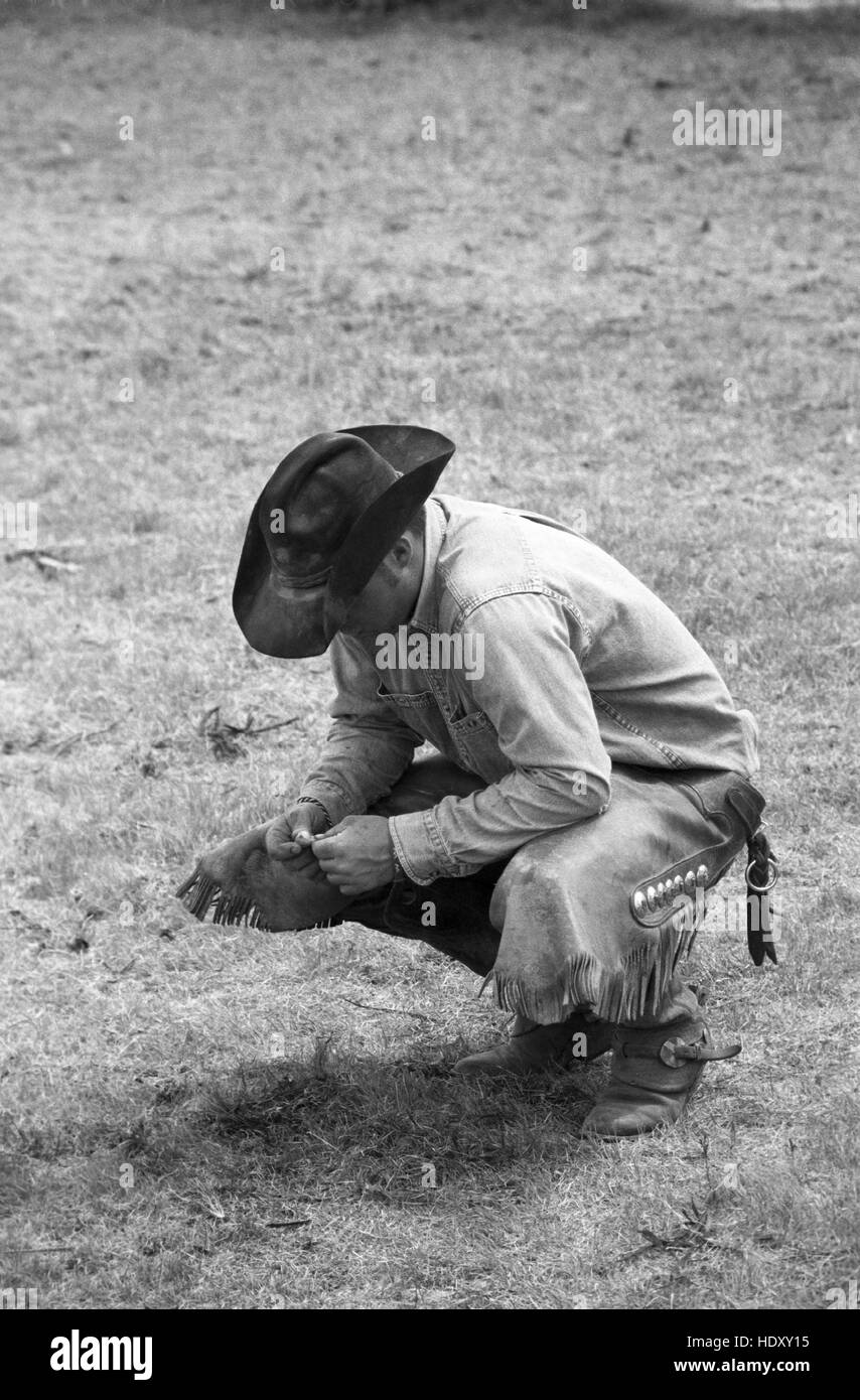 Cowboy Brandon Burton a Sandy Camp, Clarendon, TX in appoggio a primavera tempo di branding (scansione dal b&w negativo) circa 1998 Foto Stock