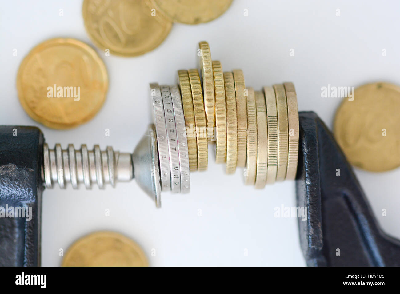 Economia concetto di pressione con la pila di monete in un crampi Foto Stock