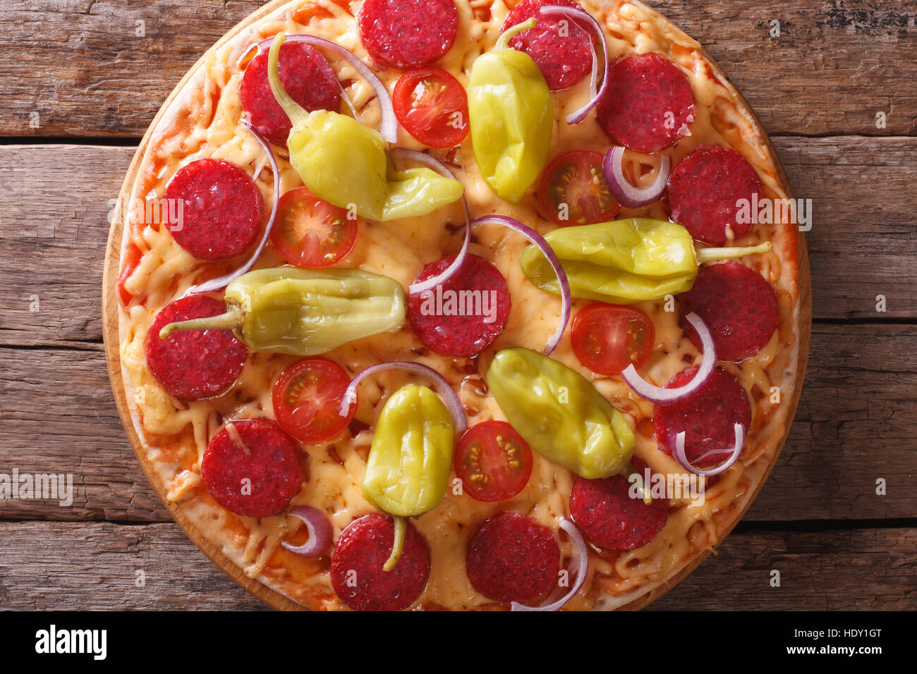 Pizza con salame e salsiccia per pizza pepe e pomodori in una tabella di close-up vista verticale dal di sopra, stile rustico Foto Stock