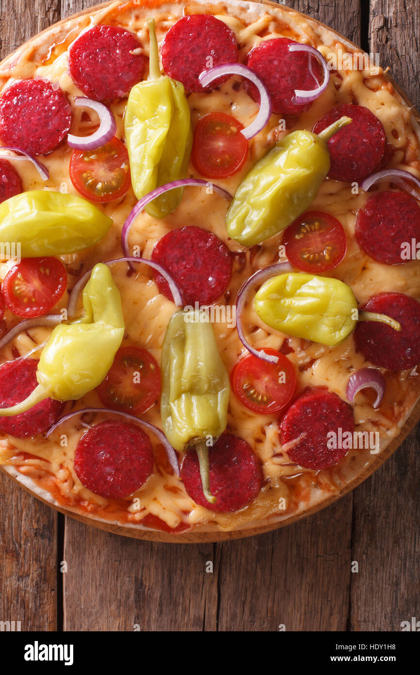 La pizza italiana con salame e salsiccia per pizza pepe e pomodori in una tabella di close-up vista verticale da sopra Foto Stock