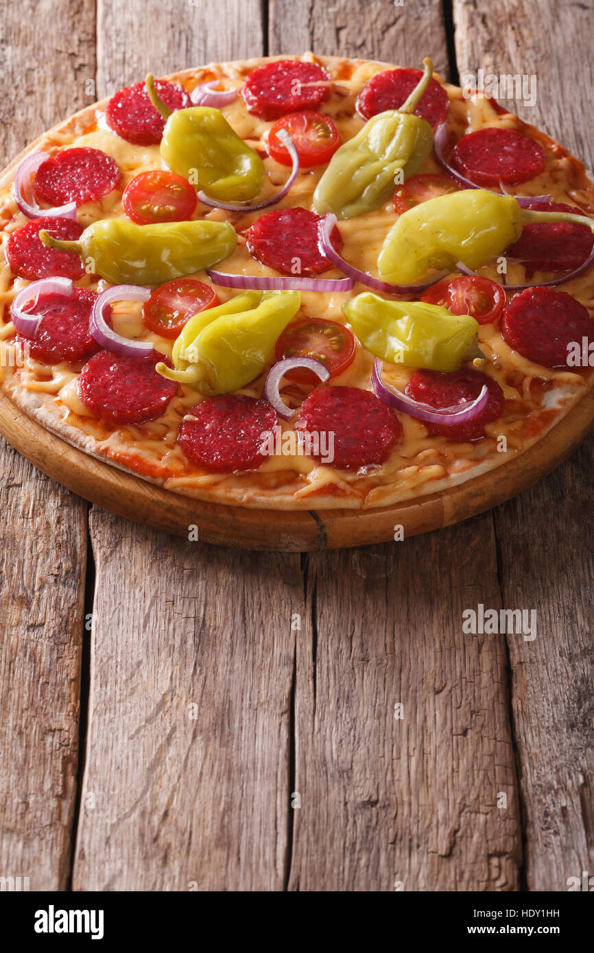 La pizza italiana con salame e salsiccia per pizza pepe e pomodori in una tavola verticale di close-up Foto Stock